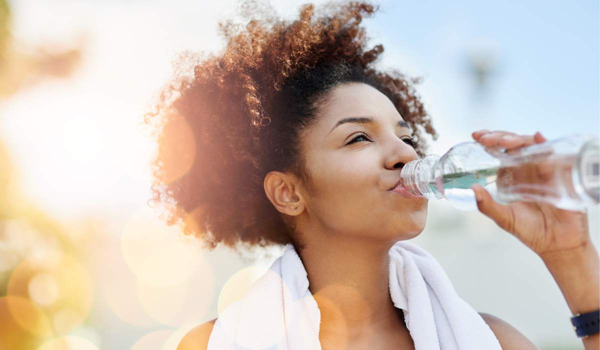mportancia-hidratacion-escalada Imagen realista de un escalador hidratándose con una botella reutilizable frente a una pared rocosa. Detalles como gotas de agua en la botella y un paisaje montañoso al fondo destacan la importancia de la hidratación en la escalada.